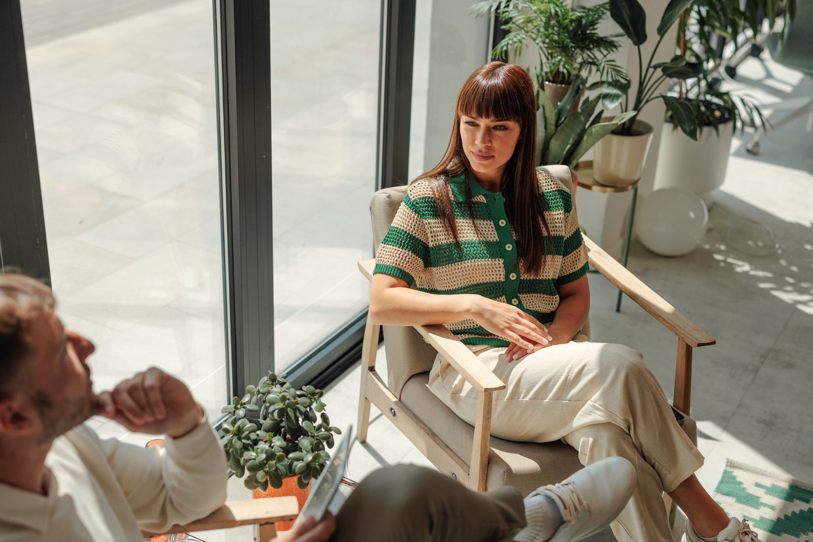 A counselor and client talking in a warm, plant-filled session