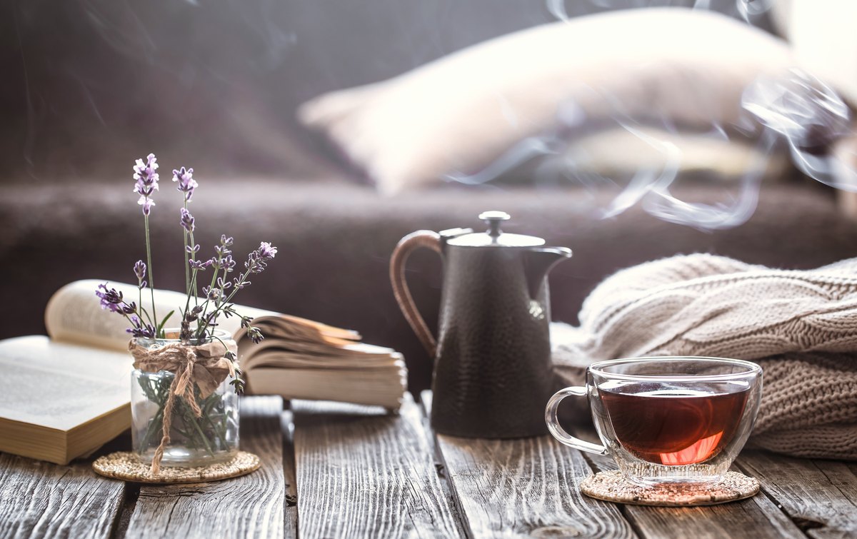 An open book with tea and lavender on a warm wooden table — reviewing a source against its origins